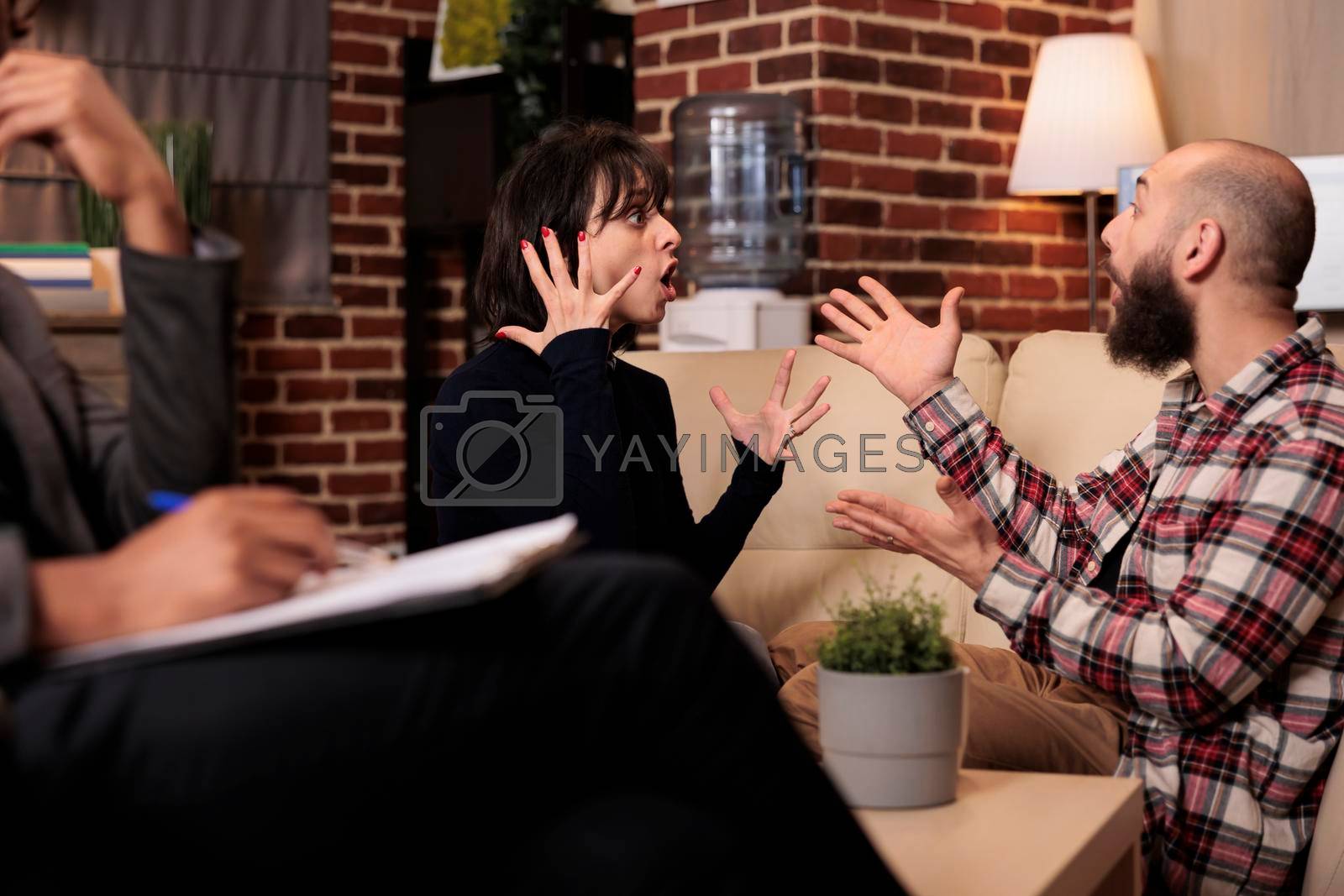 Royalty free image of Angry partners fighting at couple therapy session with specialist by DCStudio