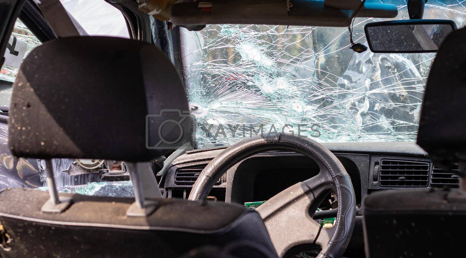 Royalty free image of Damaged car window after an accident. Broken windshield as a result of an accident, inside view. Cabin interior details, view from the cab. Safe movement. Broken windshield. Glass crack and damage. by Roshchyn