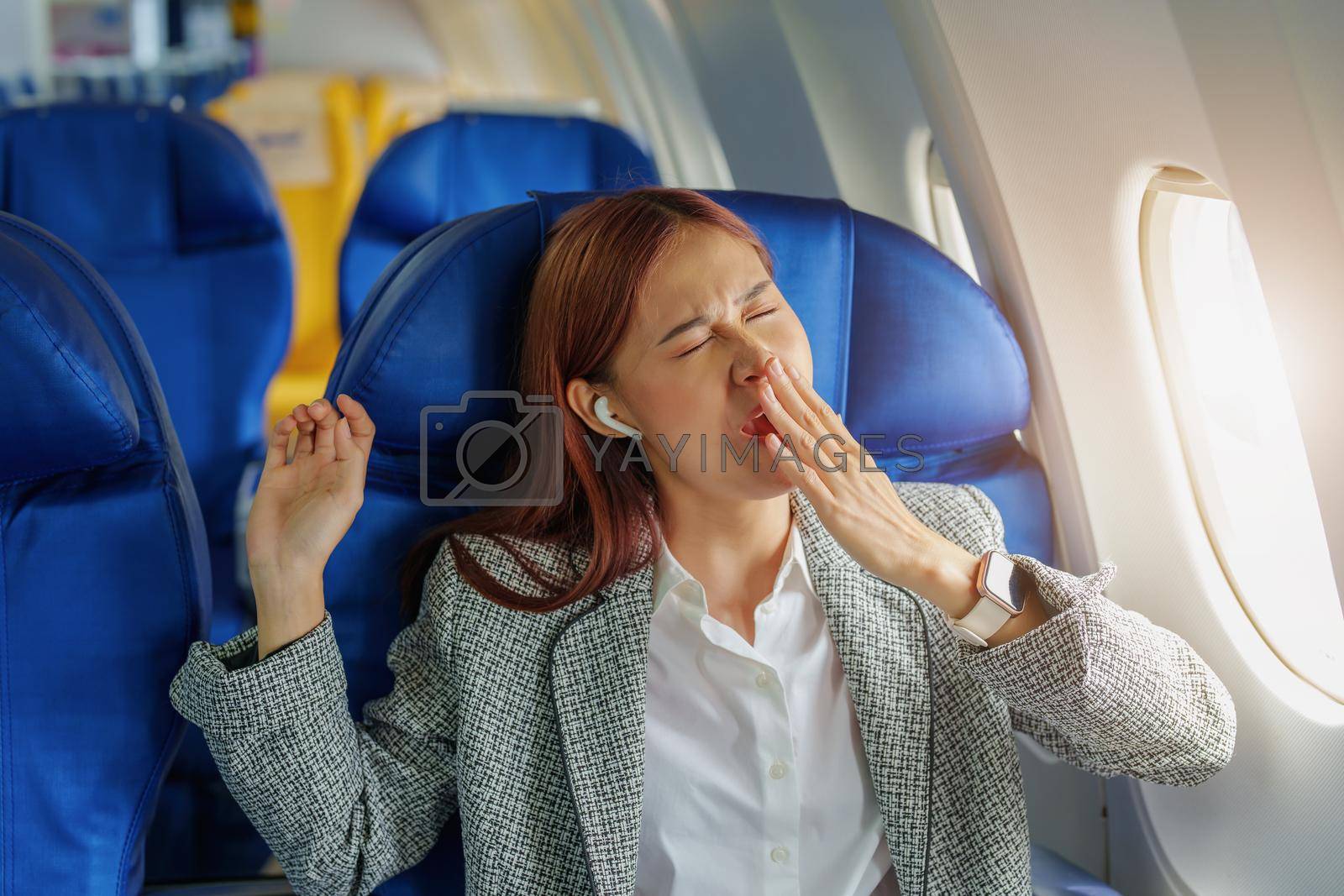 Royalty free image of Portrait of a successful Asian businesswoman or entrepreneur in a formal suit on an airplane in business class waking up from resting between flights by Manastrong