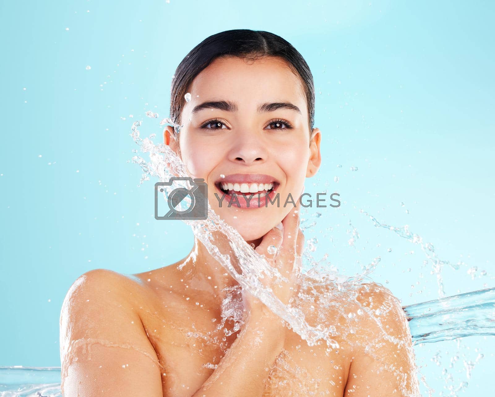Royalty free image of I scream. You scream. We all scream for eye cream. Shot of a beautiful young woman being splashed with water against a blue background. by YuriArcurs