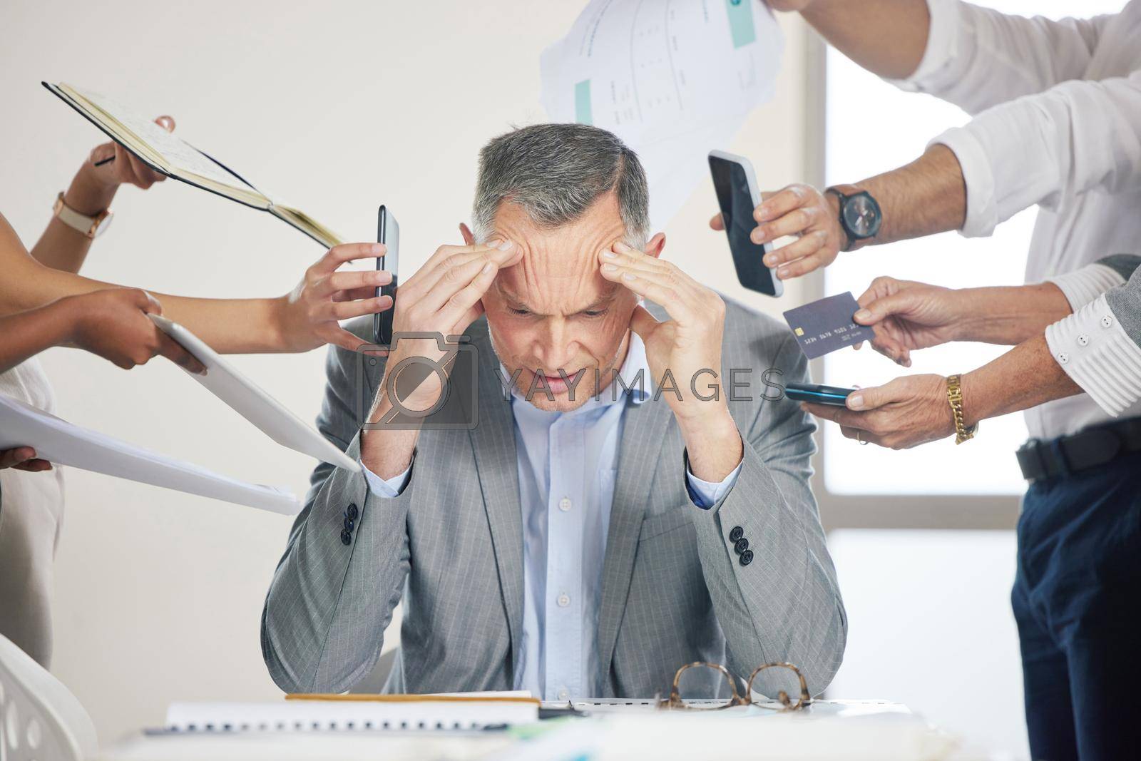Royalty free image of Could this day get any worse. a stressed older businessman being bothered by staff. by YuriArcurs