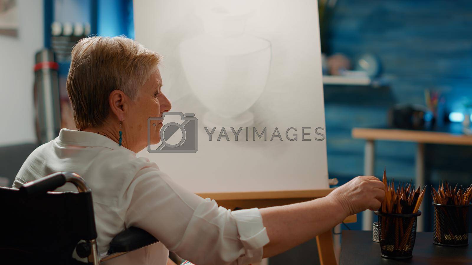 Royalty free image of Retired person with health condition using pencils to draw vase design by DCStudio