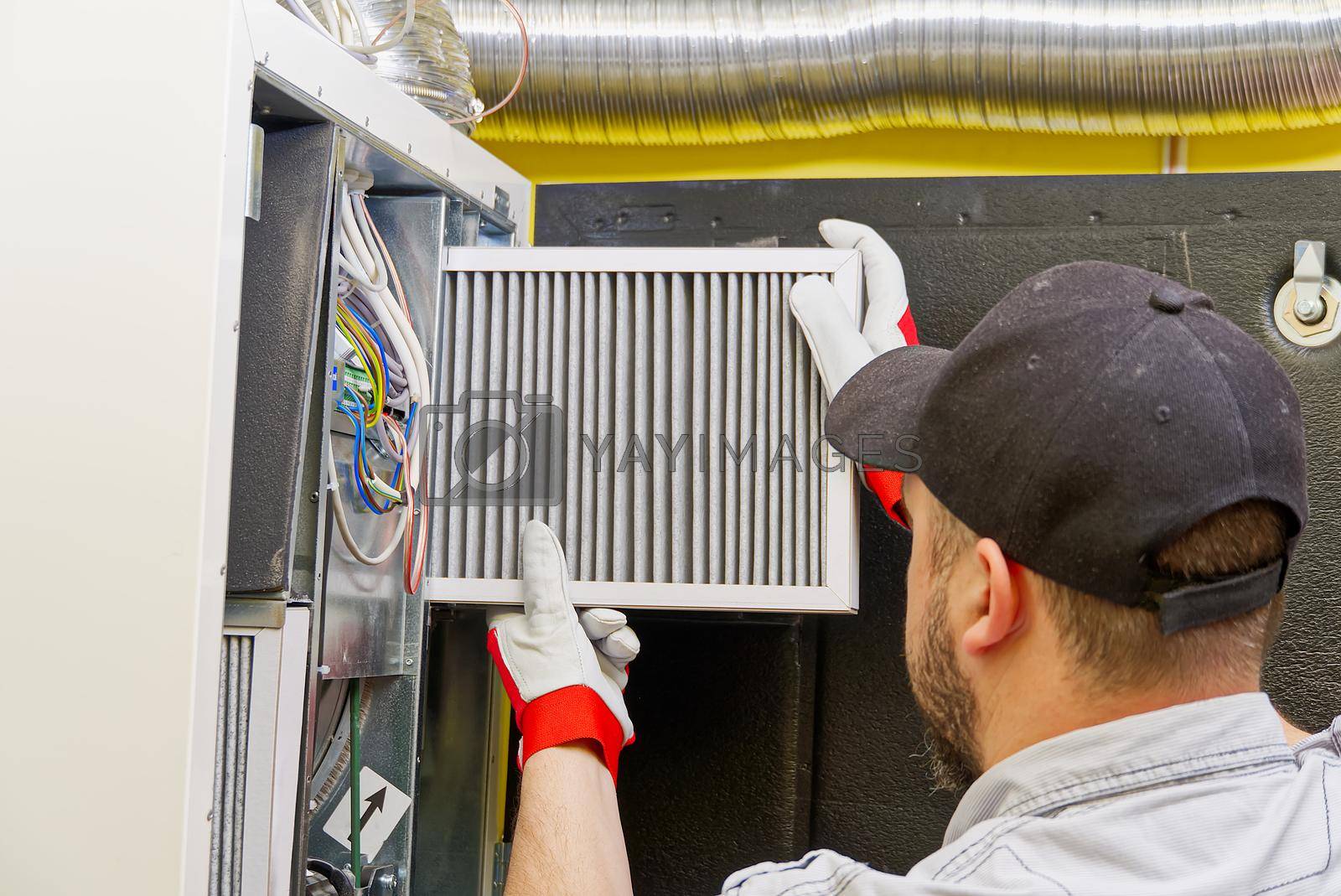 Royalty free image of HVAC service technician changing dirty air filter in the central ventilation system by PhotoTime