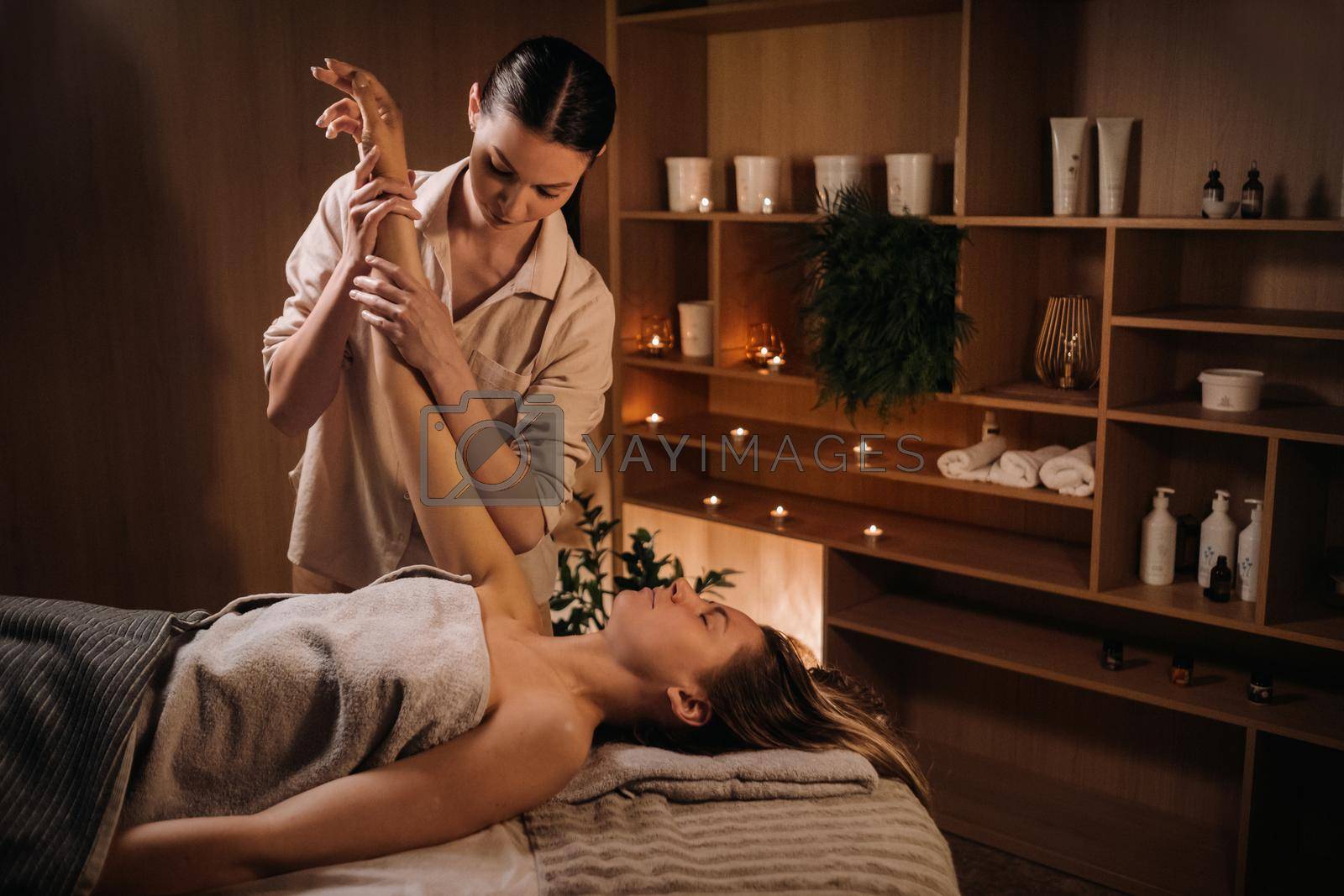 Royalty free image of A masseuse gives a hand massage to a woman in a spa center. A professional masseur massages the hand of a girl lying in a spa center by Lobachad