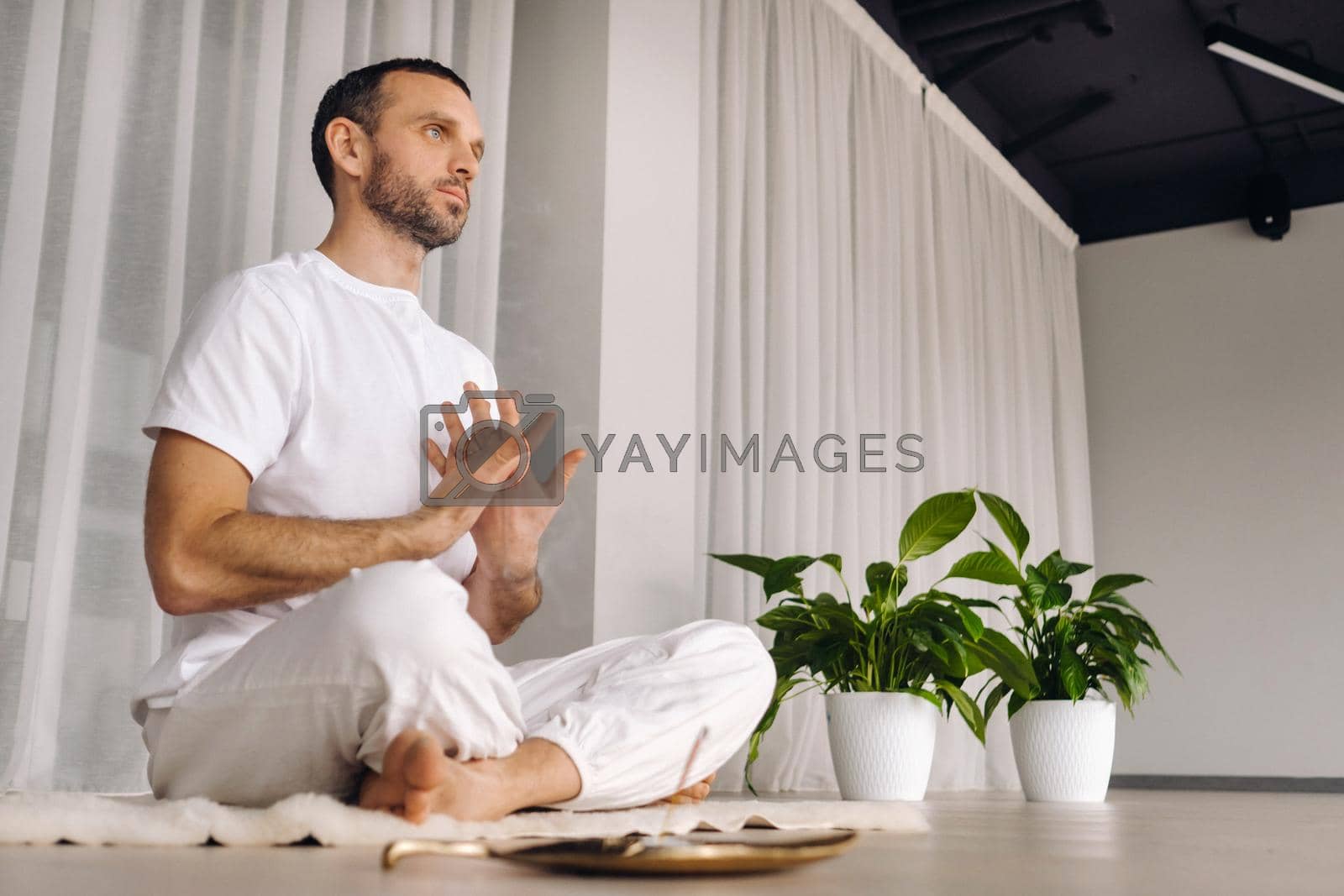 Royalty free image of Close-up of a man in white sportswear doing yoga in a fitness room with a balgovon. the concept of a healthy lifestyle by Lobachad