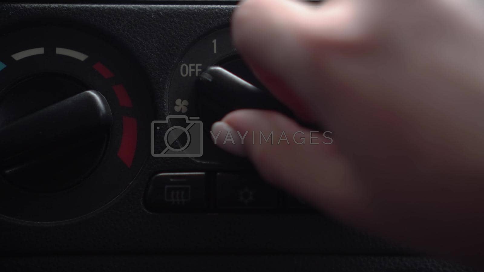 Royalty free image of The woman turns on the fan and presses the air conditioner button in the car. Automotive panel close-up. by Puzankov