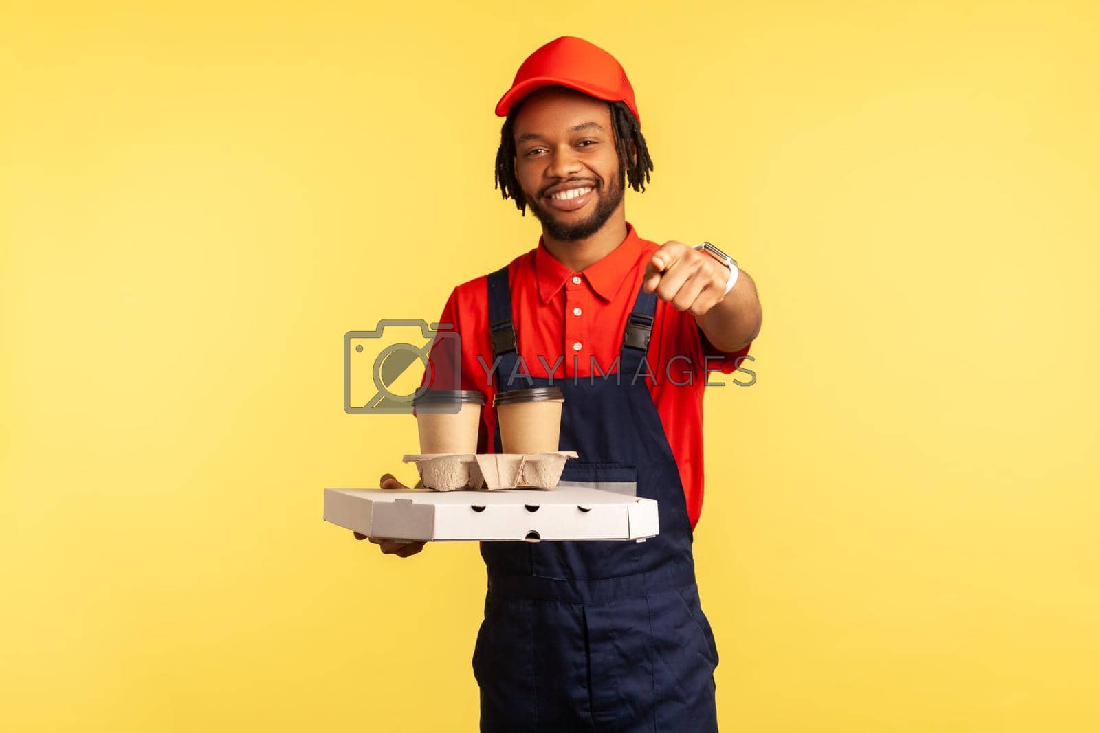 Royalty free image of Deliveryman holding coffee and pizza in cardboard box, pointing at camera, your delivery order. by Khosro1