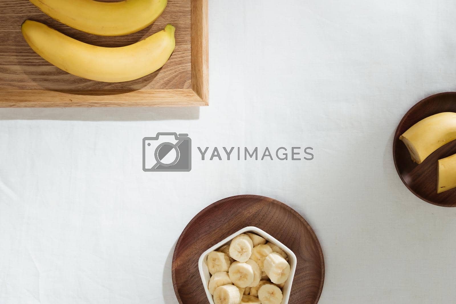 Royalty free image of Bananas and banana pieces in a wooden plate by makidotvn