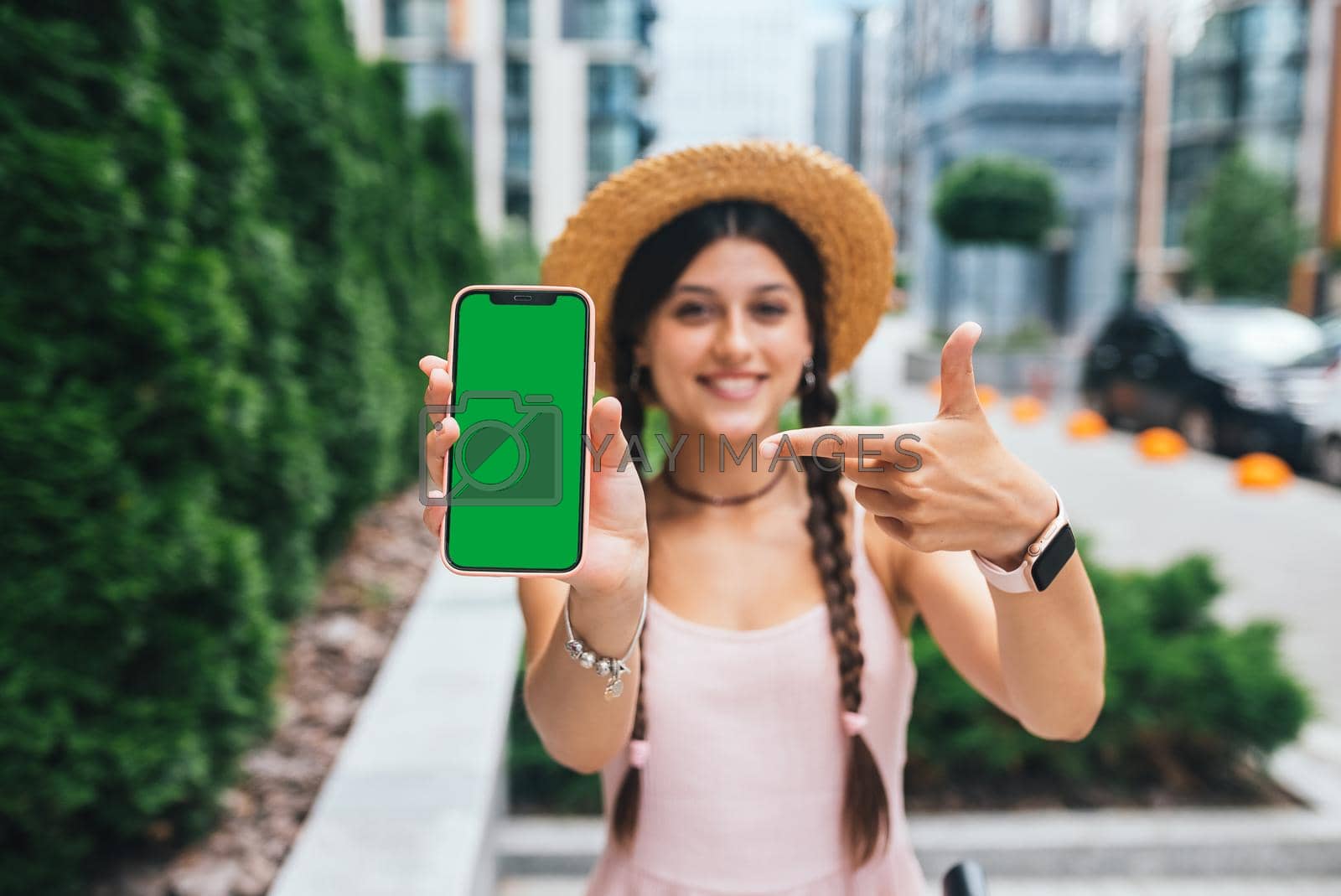 Royalty free image of woman showing modern smartphone with green screen for replacement by teksomolika