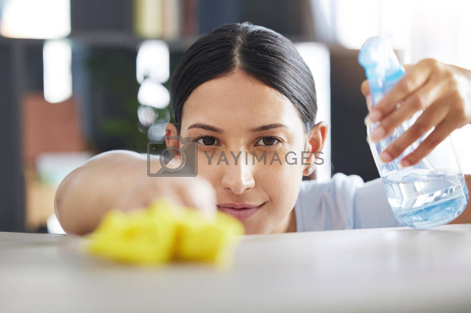 Royalty free image of One beautiful young mixed race woman cleaning the surfaces of her home. Hispanic domestic worker wiping a table by YuriArcurs