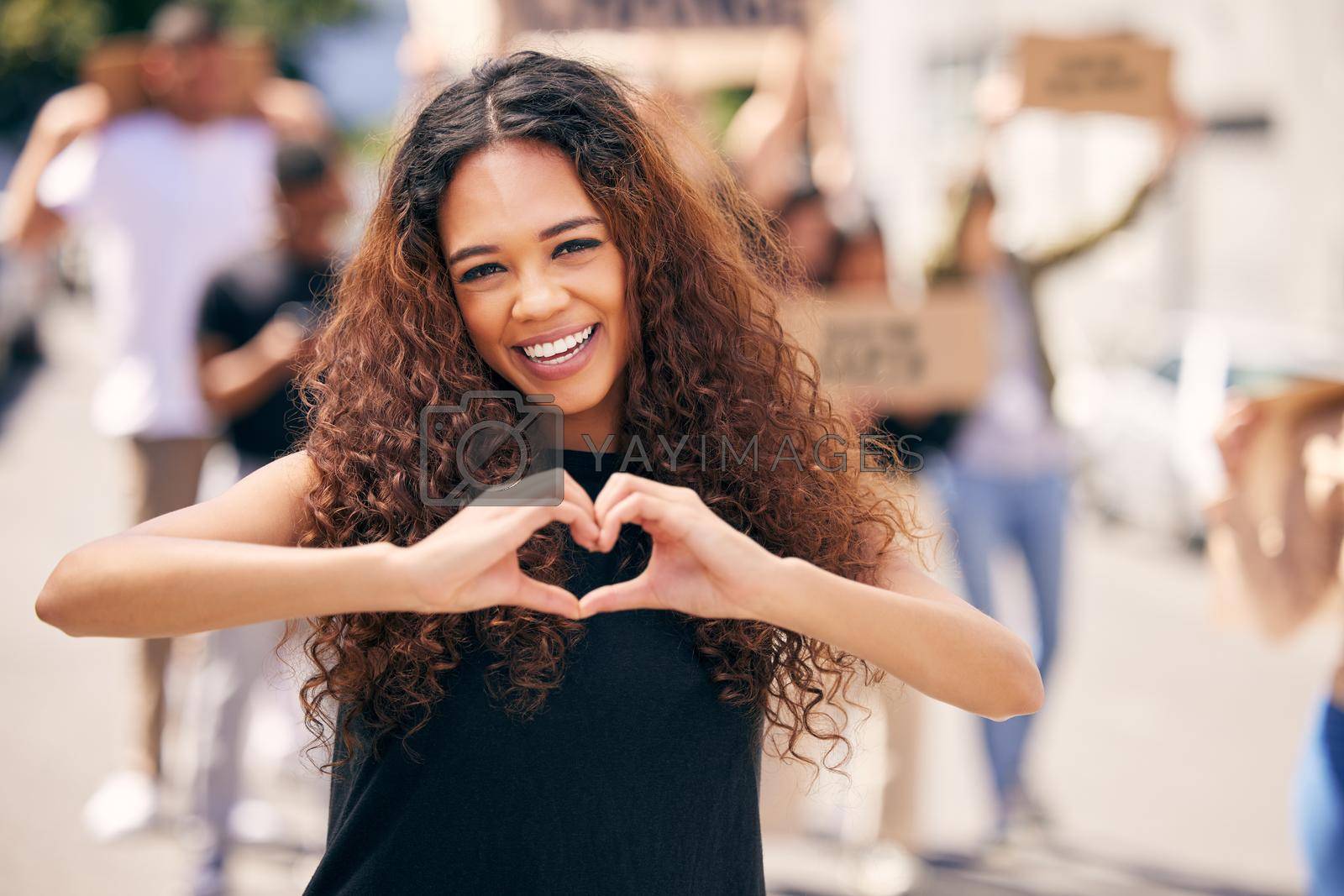 Royalty free image of Spreading love not hate. a young female protestor forming a heart shape at a protest rally. by YuriArcurs