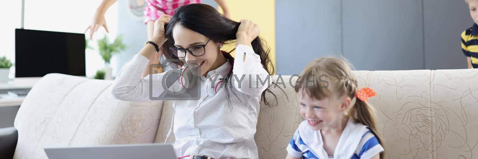 Royalty free image of Happy woman working and playing with her kids on couch by kuprevich