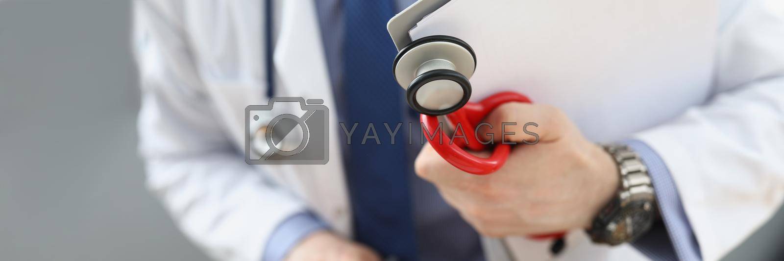 Royalty free image of Doctor holding medical equipment red stethoscope and patient medical history by kuprevich