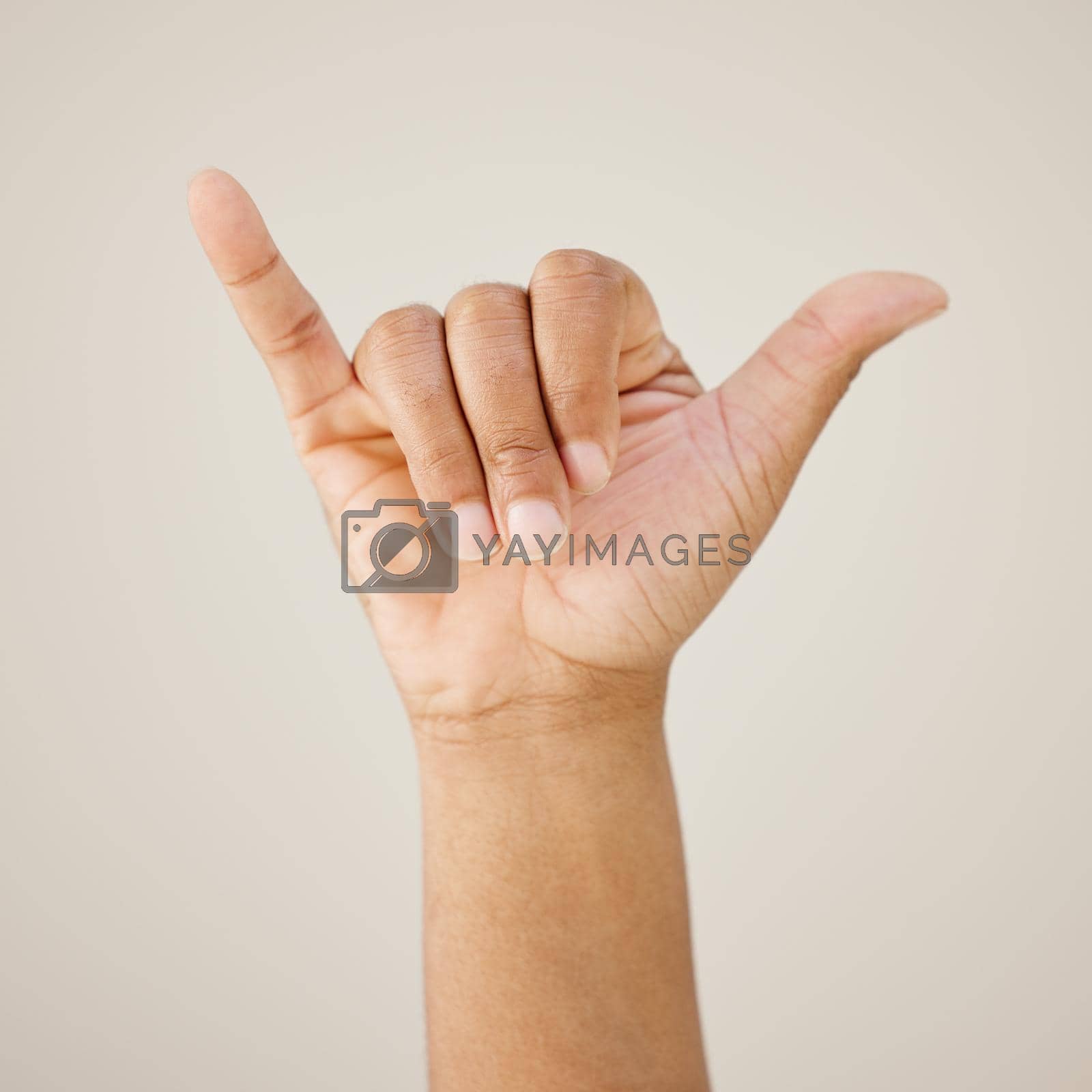 Royalty free image of Hit me up. a man showing a hand sign against a studio background. by YuriArcurs
