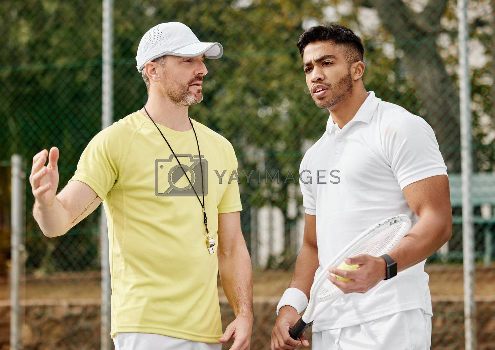 Royalty free image of Whats the best course of action here. a handsome male coach giving instructions to his younger tennis student on a court. by YuriArcurs