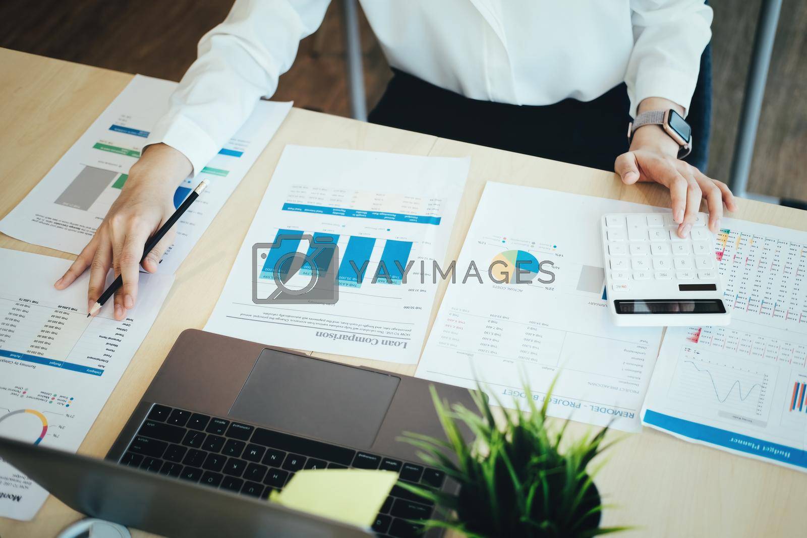 Royalty free image of focus woman holding a pencil Auditors use budget document calculators to find annual budget disbursement errors. by Manastrong