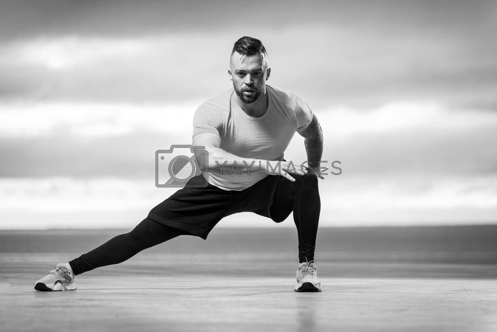 Royalty free image of Athletic man doing fitness exercises on the ocean beach by MikeOrlov