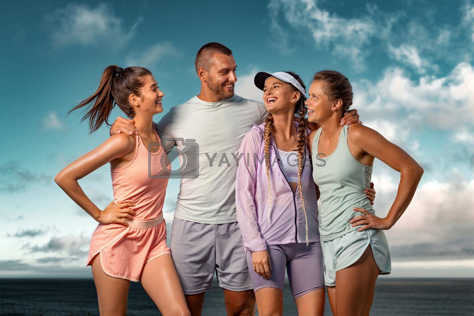 Royalty free image of Smiling women and man fitness team. A happy group of runners rest after running along the sea coast early in the morning. by MikeOrlov