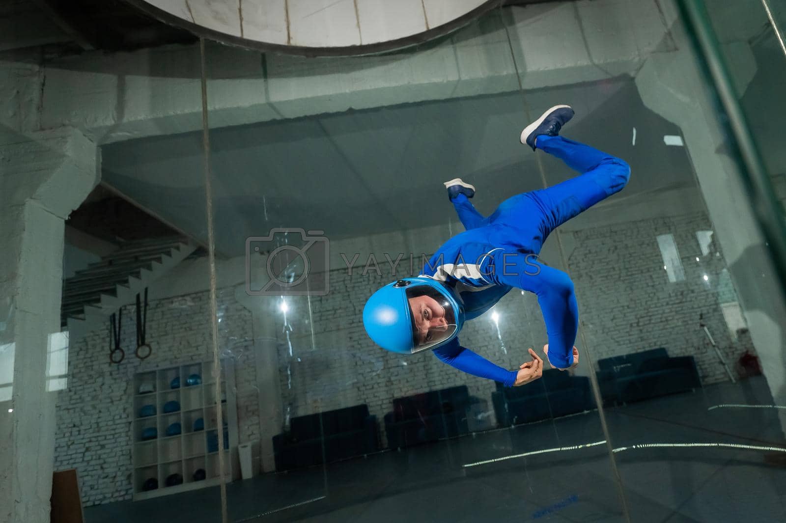 Royalty free image of A man in overalls and a protective helmet enjoys flying in a wind tunnel. Free fall simulator by mrwed54