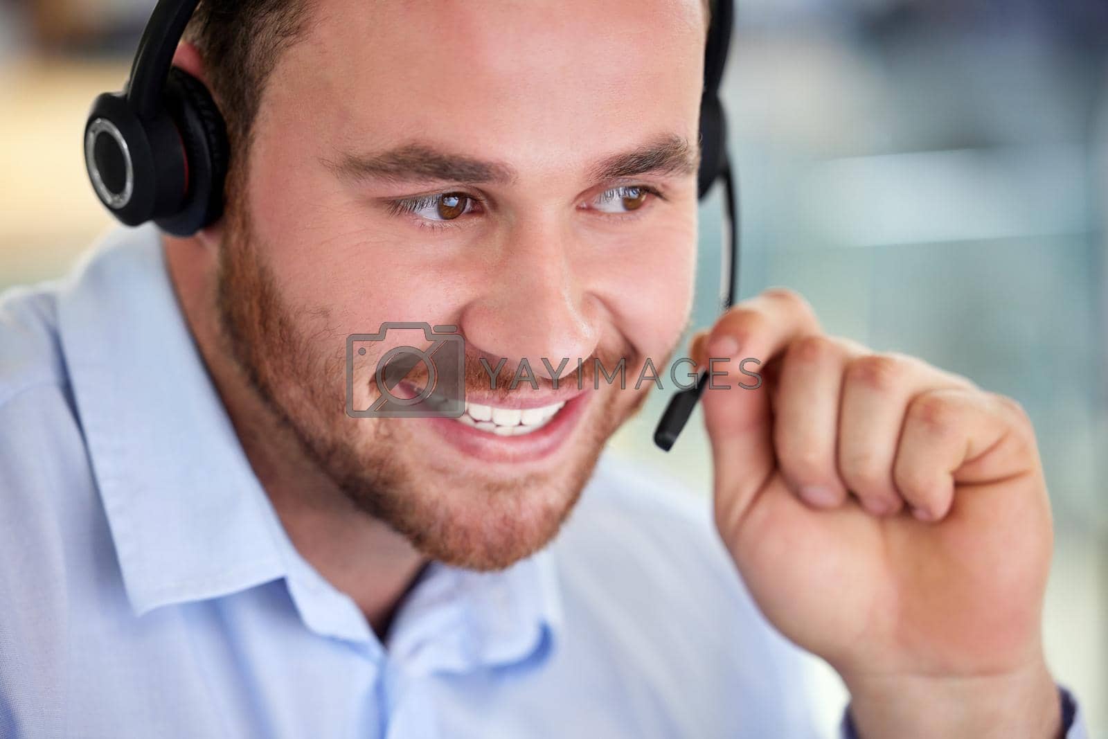 Royalty free image of Professional assistance at your service. a young man using a headset in a modern office. by YuriArcurs