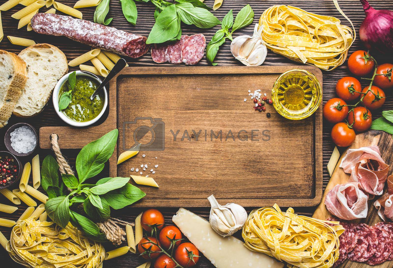 Top view of Italian traditional food, appetizers and snacks as salami, prosciutto, cheese, pesto, ciabatta, olive oil, pasta on rustic wooden board with space for text and retro style