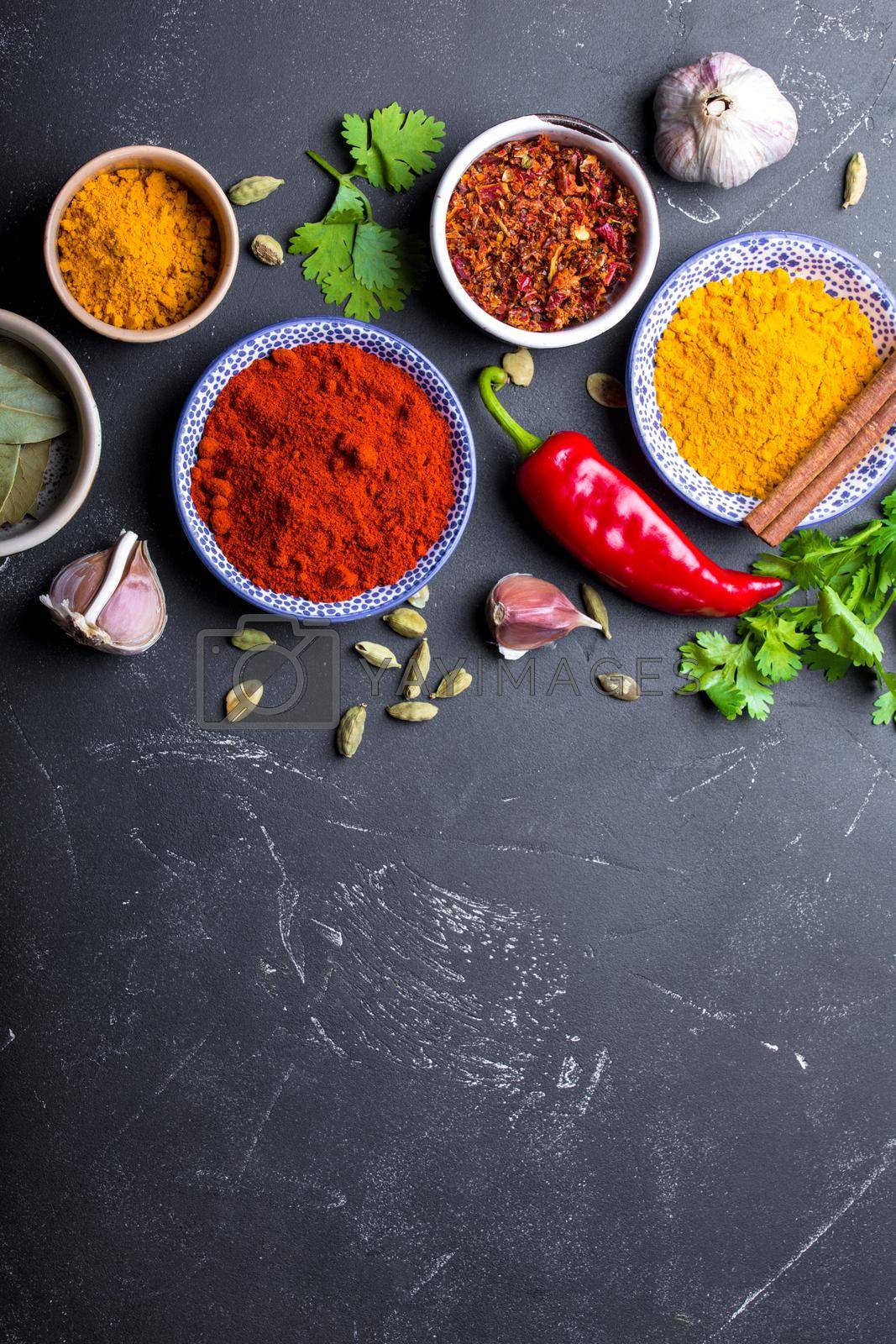 Close-up of Indian food cooking background. Traditional Indian spices and ingredients. Curry, turmeric, cardamom, garlic, pepper, cilantro, cinnamon. Preparing exotic meal. Top view, space for text