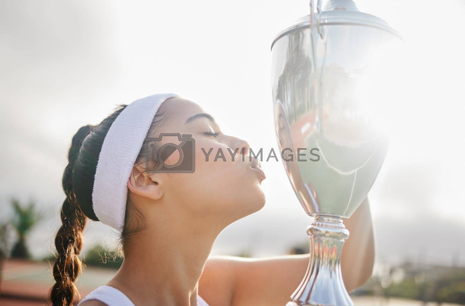 Royalty free image of Winning is a way of expressing yourself. an attractive young tennis player holding up a trophy. by YuriArcurs
