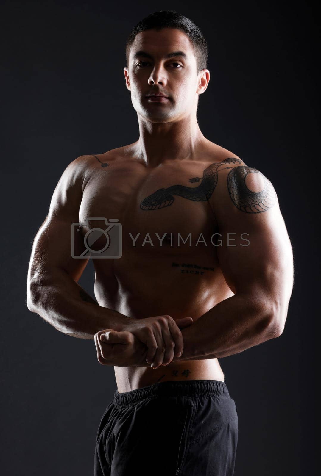 Royalty free image of Flex now, talk later. athletic young man flexing his muscles while posing against a dark background. by YuriArcurs