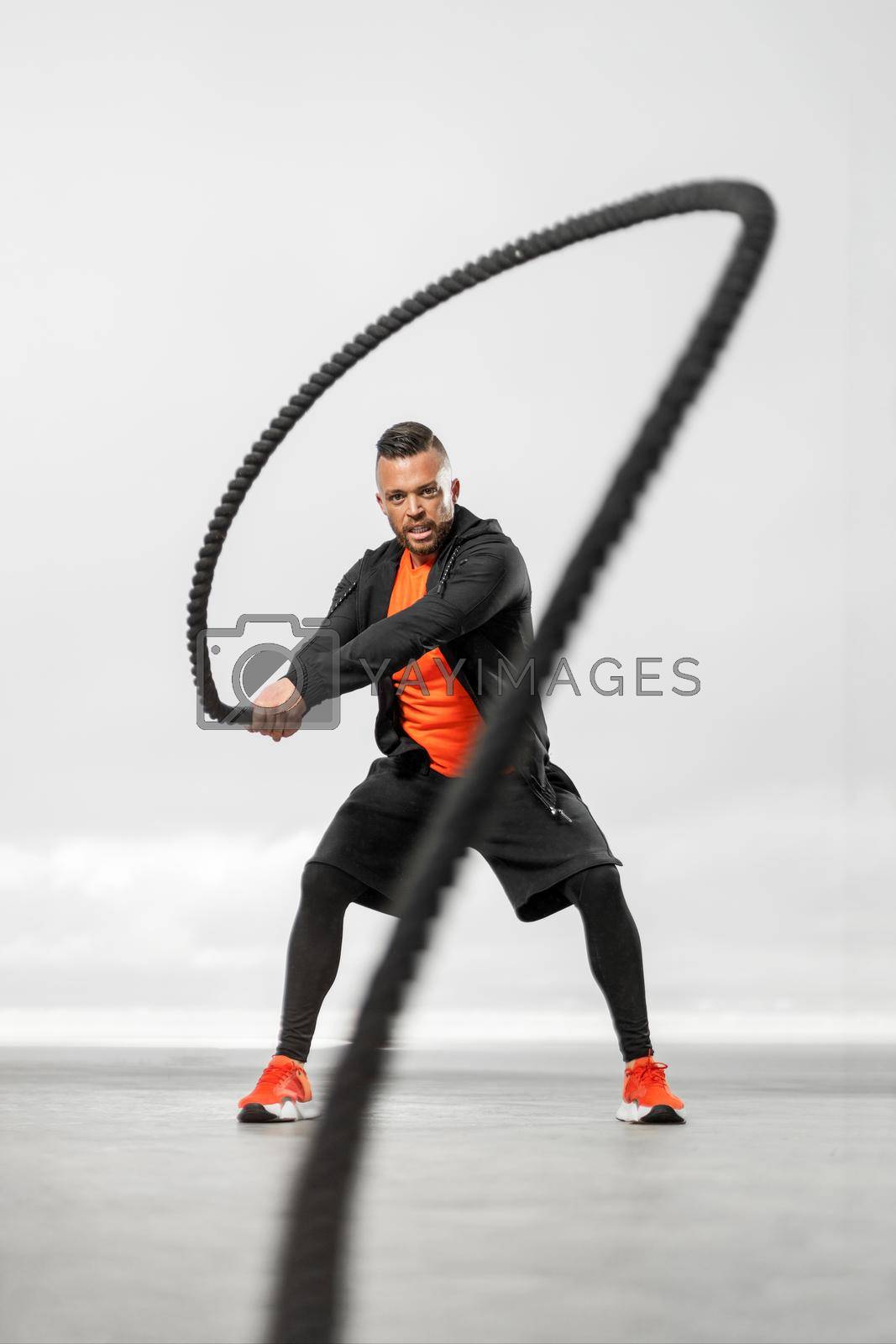 Royalty free image of Athletic man with a battle rope doing fitness exercises for fat burning. by MikeOrlov