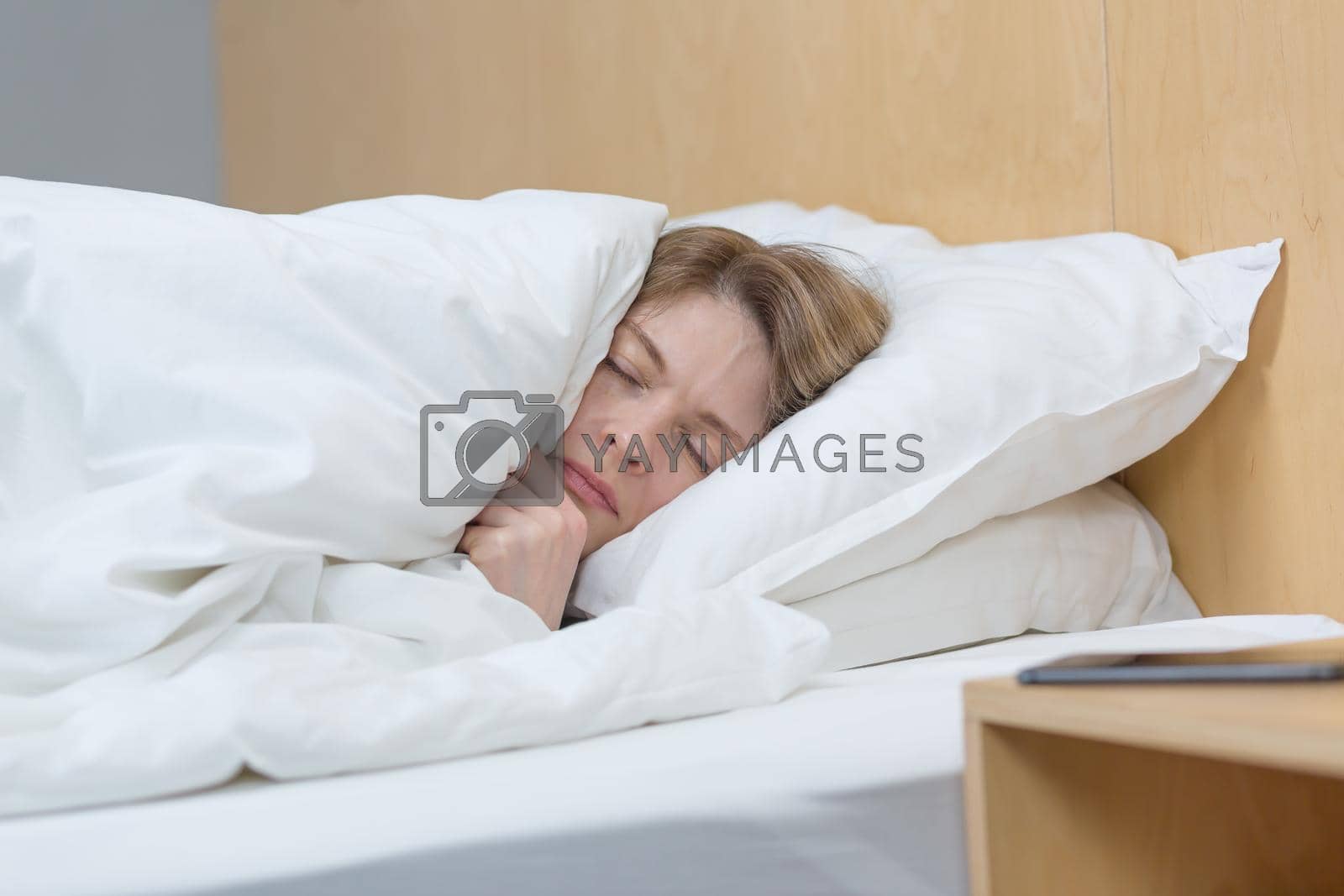 Royalty free image of Close-up photo of a sleepless and upset woman lying in bed under a blanket, trying to fall asleep by voronaman