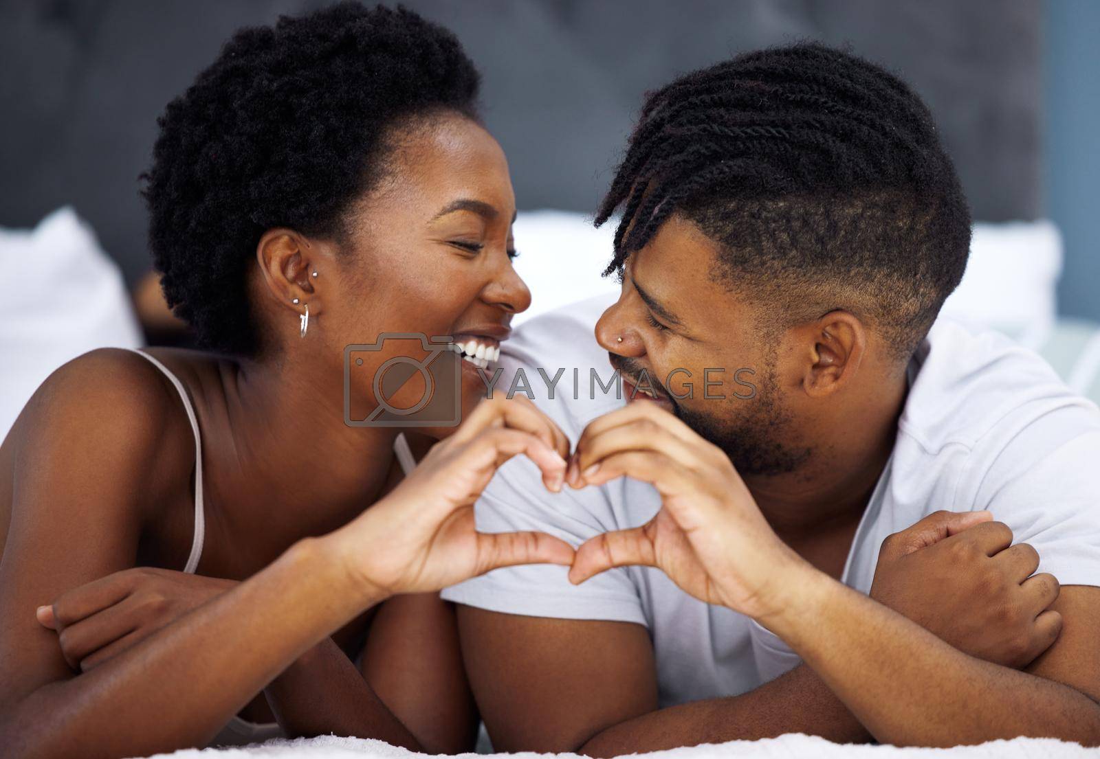 Royalty free image of You have my heart for keeps. a young couple making a heart shaped gesture in bed at home. by YuriArcurs