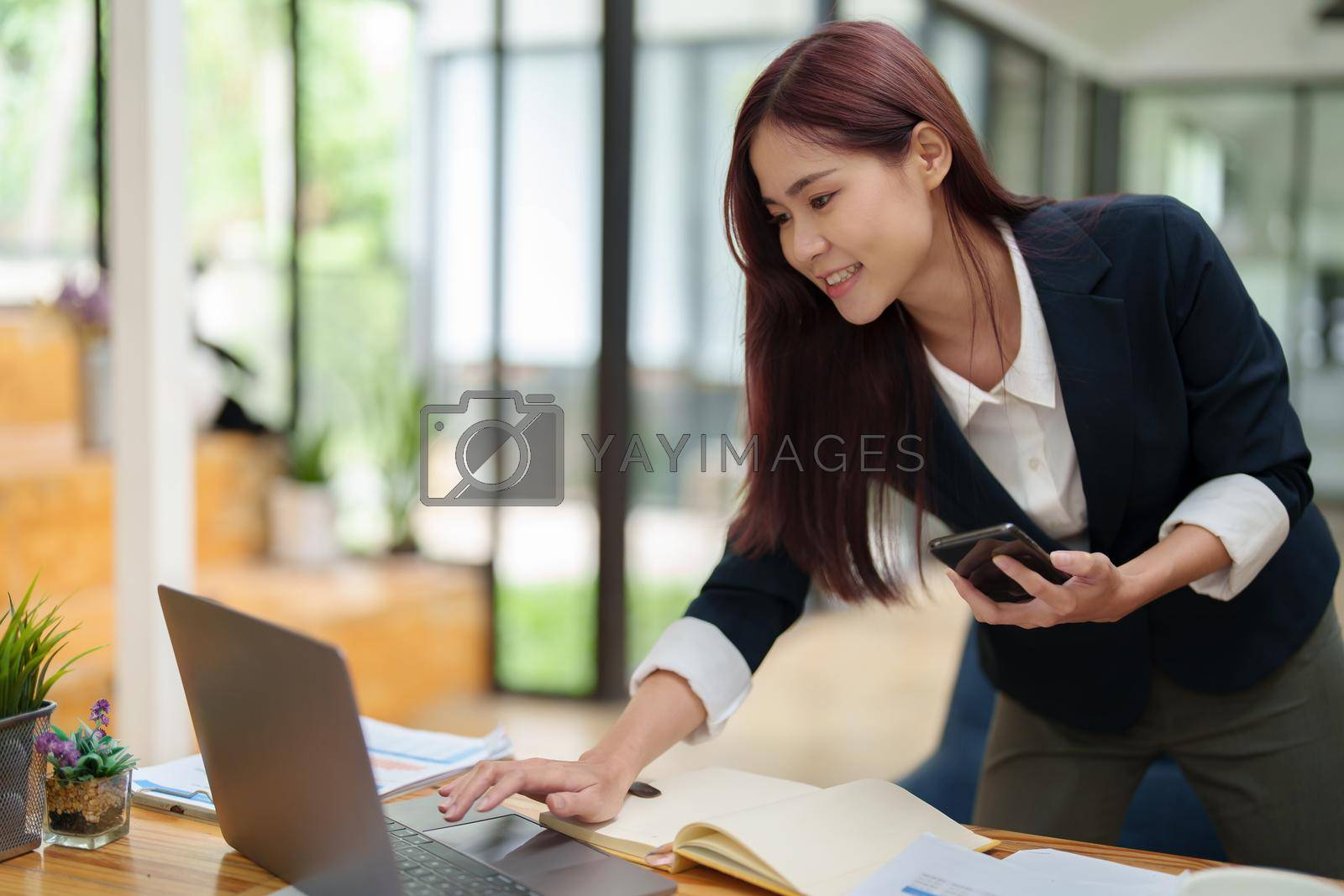 Royalty free image of Asian businesswoman using the phone to contact a business partner by Manastrong
