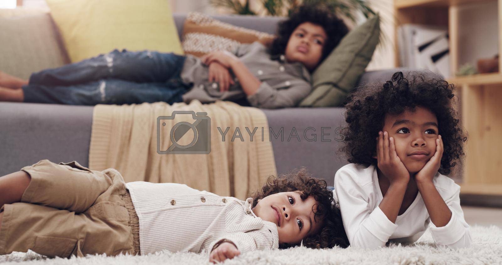 Royalty free image of Waiting for our favourite cartoon to begin. three adorable little boys laying and watching tv together at home. by YuriArcurs