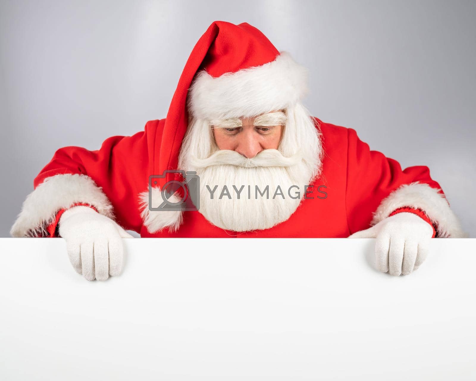 Royalty free image of Santa Claus peeks out from behind an ad on a white background. Merry Christmas. by mrwed54