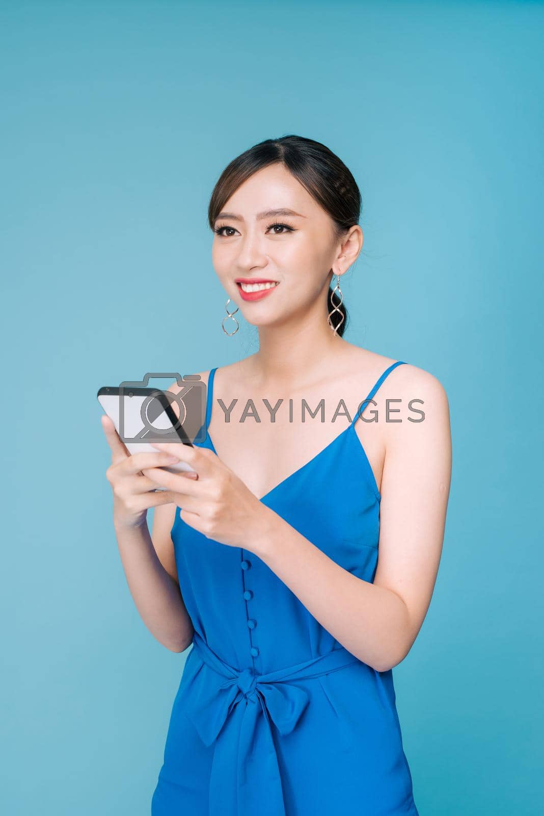 Royalty free image of Attractive woman using text messaging feature on her portable device in studio by makidotvn