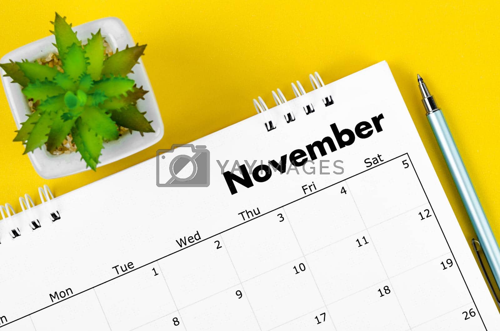 Royalty free image of The November 2022 desk calendar and pen with plant pot on yellow background. by Gamjai