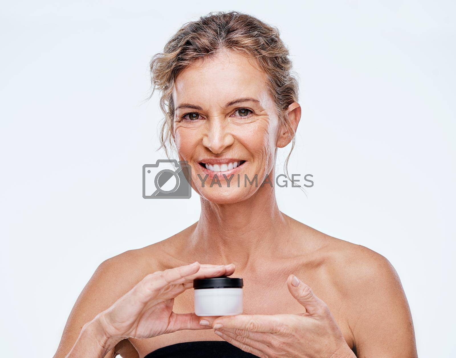 This is my secret. a mature woman holding up a beauty product against a while background