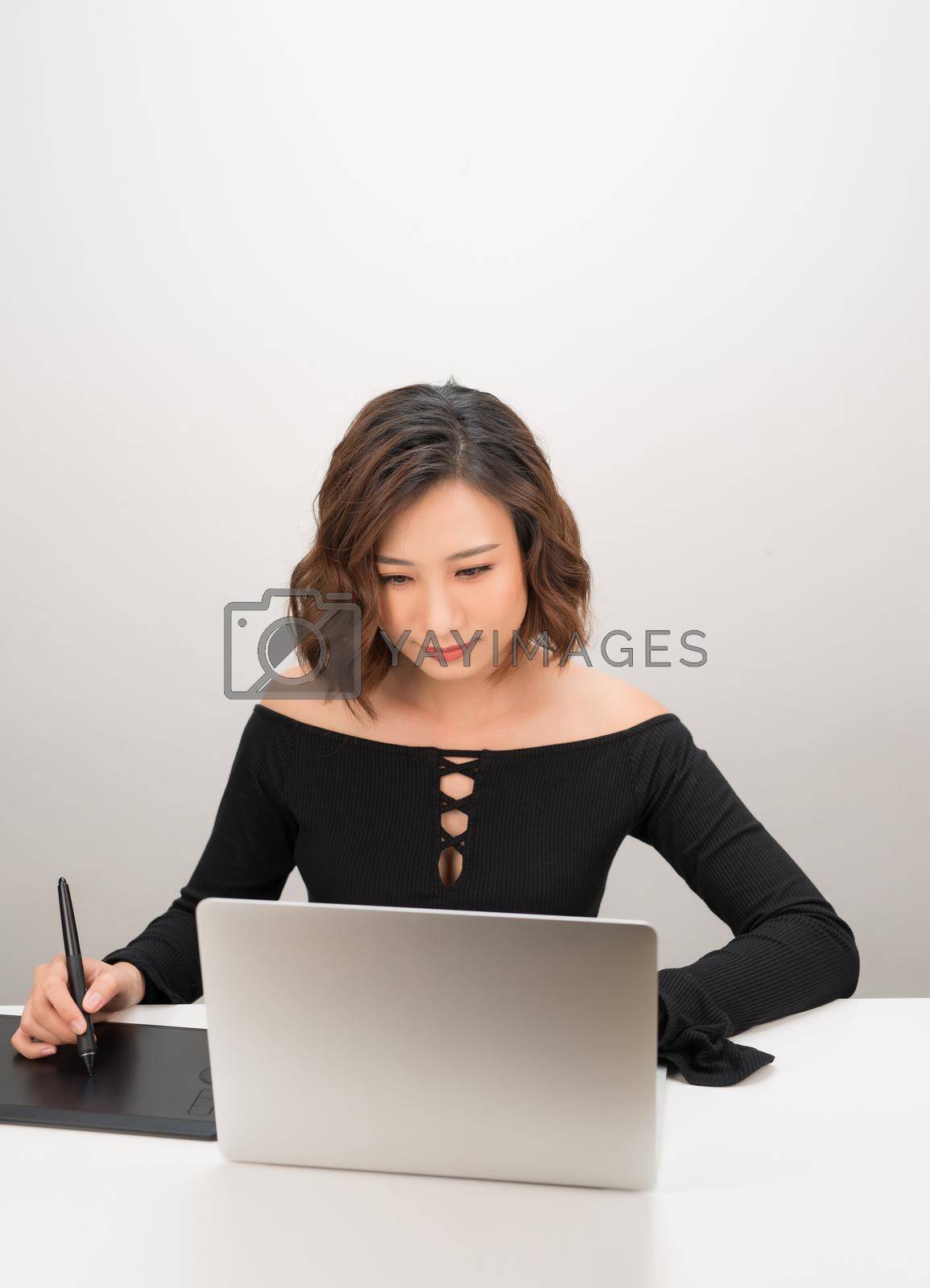 Royalty free image of Young Asian female designer using graphics tablet while working with computer by makidotvn