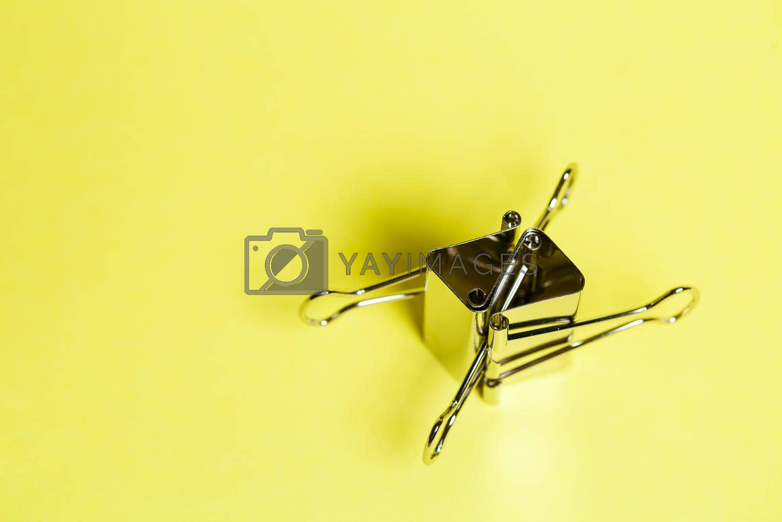 Royalty free image of Metal binders on a yellow background. Stationery accessories. Paper clip by Dmitrytph