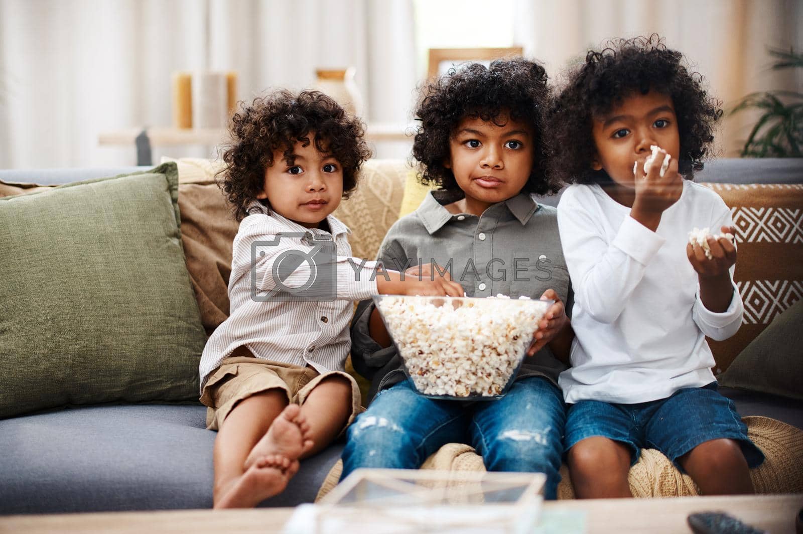 Royalty free image of Boys will be boys. three adorable little boys eating popcorn and watching movies together at home. by YuriArcurs