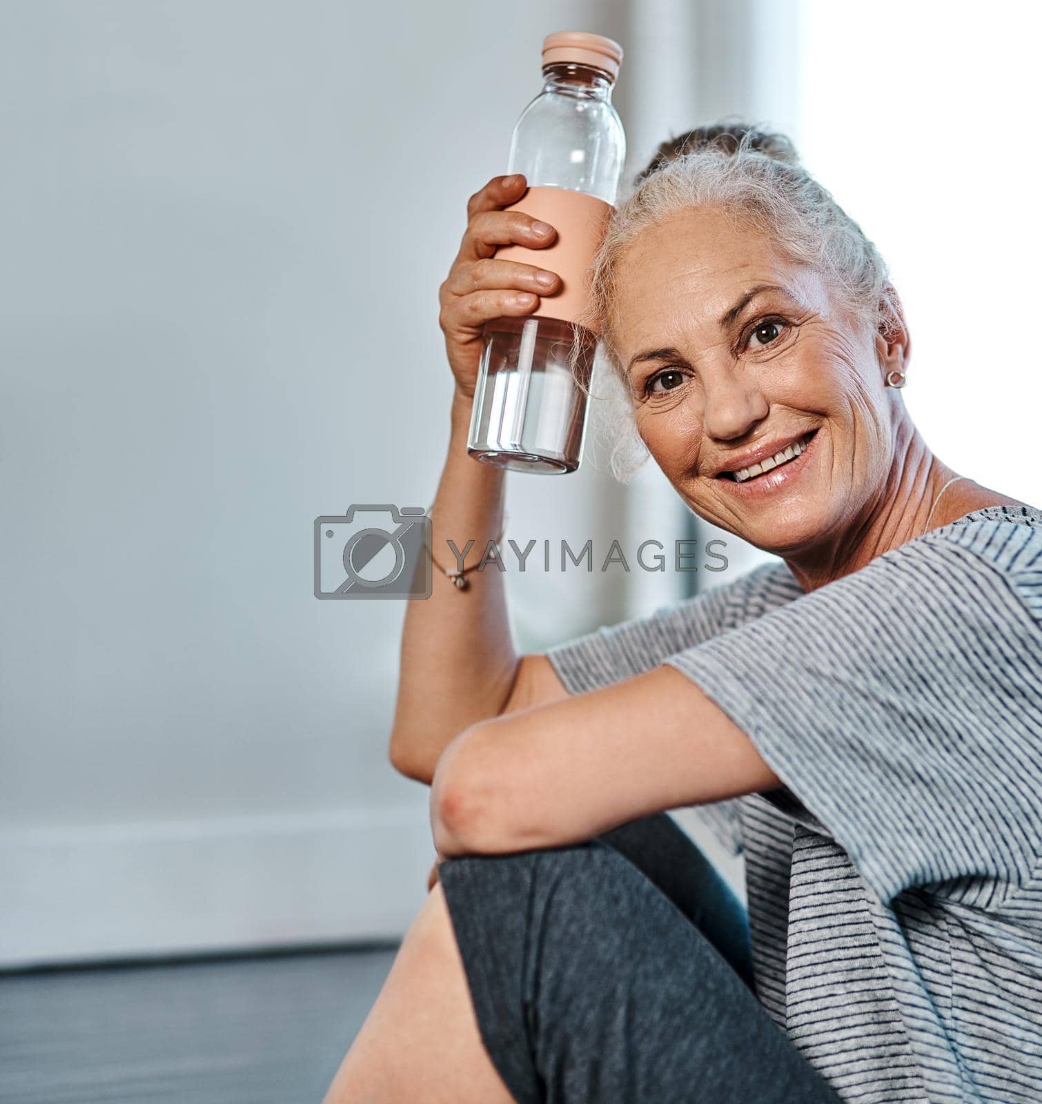 That was a great yoga session. Portrait of a cheerful mature woman practicing yoga while having a drink of water inside of a studio during the day