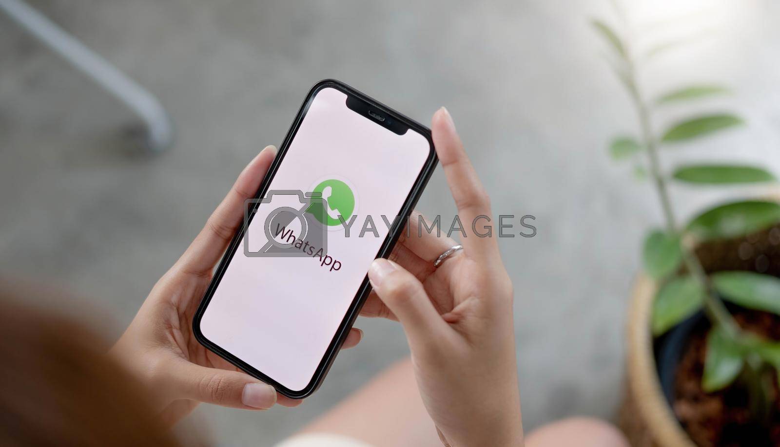 Royalty free image of CHIANG MAI, THAILAND - JUL 10 2022 : Man holding a iPhone and open appstore searching social Internet service WhatsApp on the screen. iPhone was created and developed by the Apple inc. by wichayada