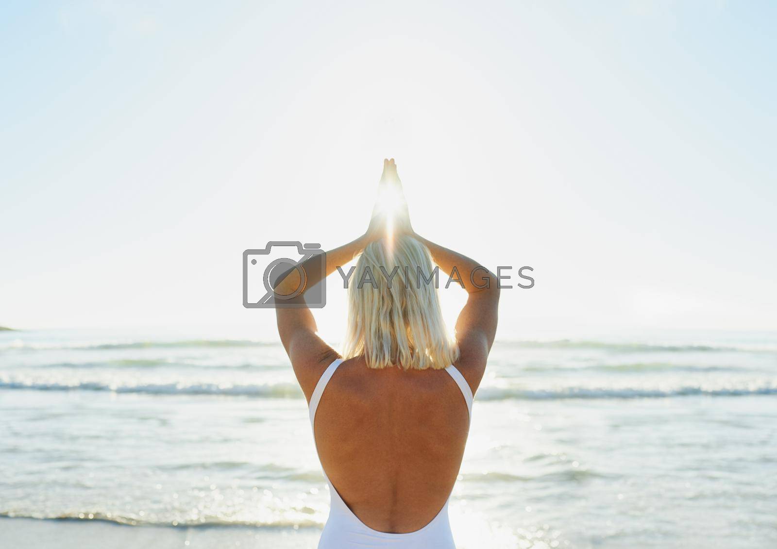 Royalty free image of I draw my focus from the sun. an unrecognizable woman in a swimsuit doing yoga early in the morning on the beach. by YuriArcurs