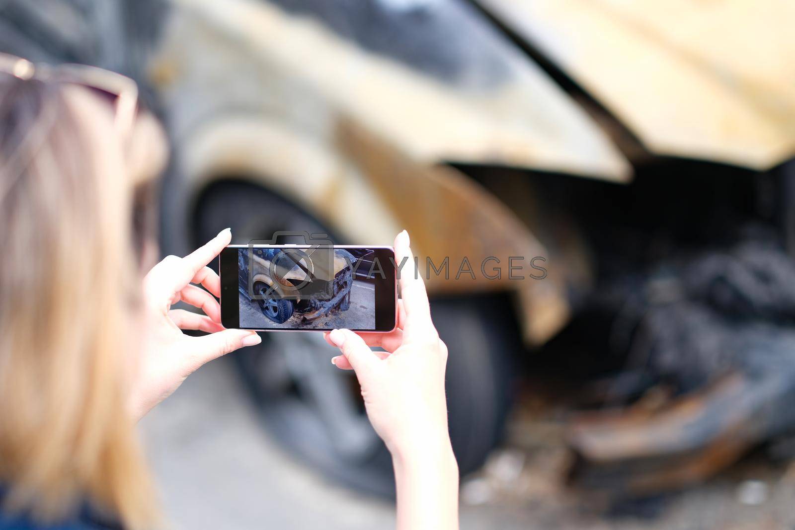 Royalty free image of Closeup of female insurance broker taking photos of car after fire accident by kuprevich