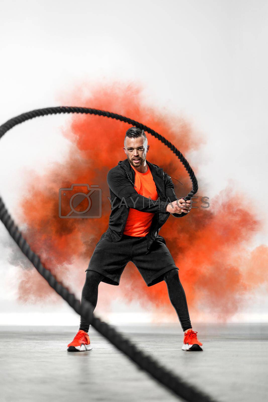 Royalty free image of Battle rope functional training. Man on cross exercises. Fit athletic man doing fitness outdoors. by MikeOrlov