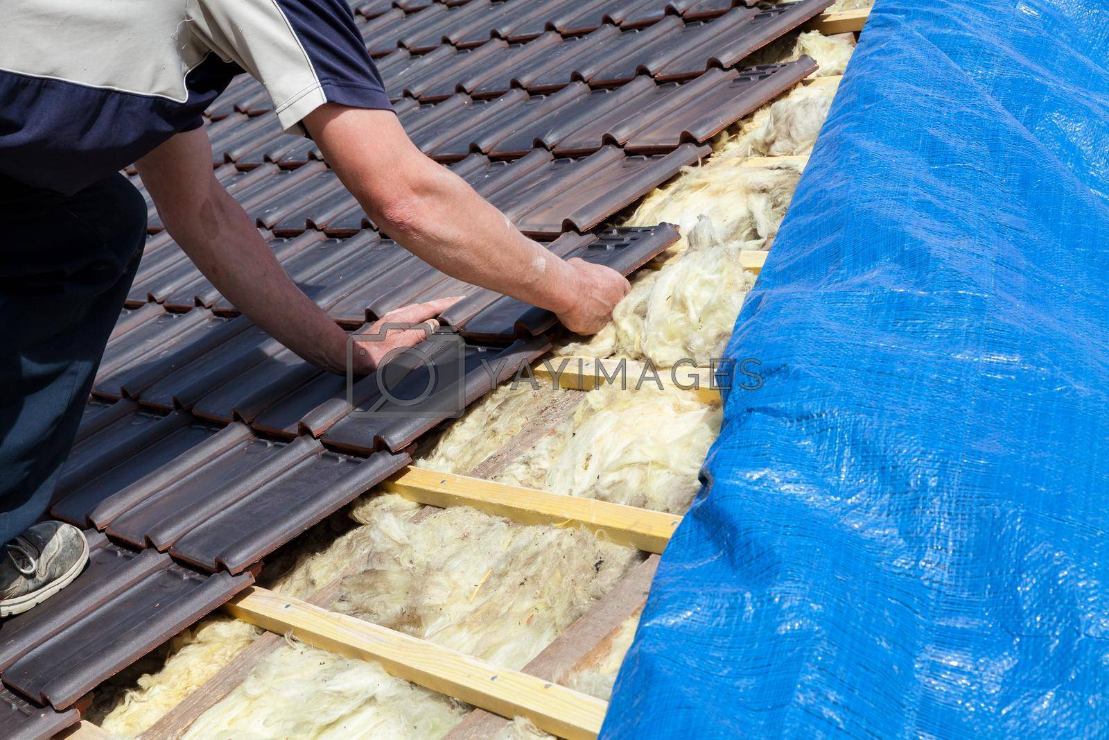 Royalty free image of a roofer laying tile on the roof by jp_chretien