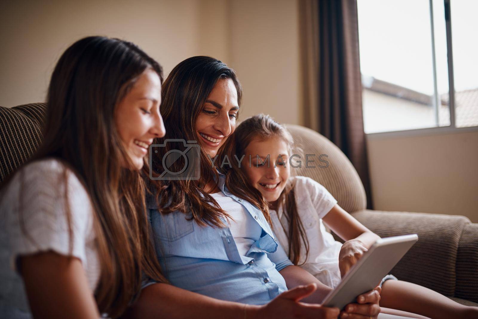 Royalty free image of Watching their favourite movie. an attractive mother watching movies on a tablet with her two daughters at home. by YuriArcurs
