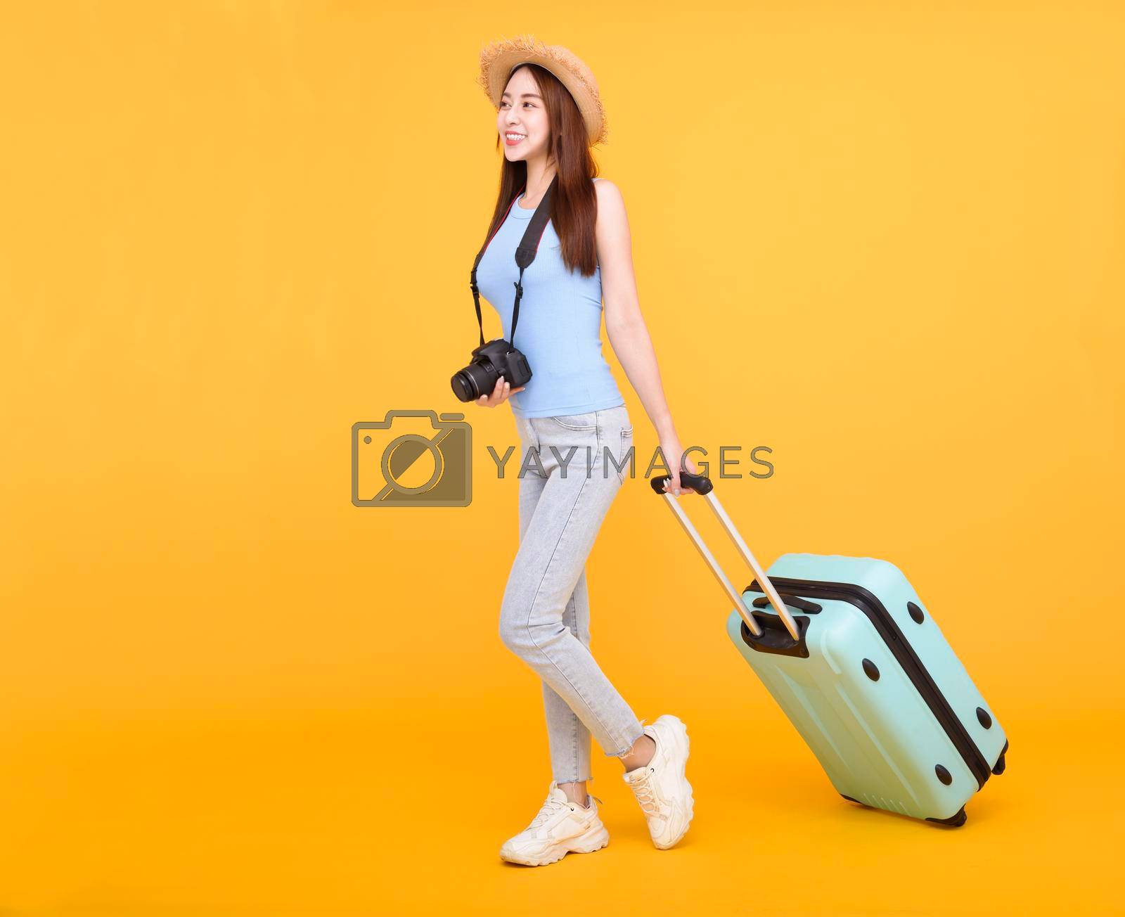 Royalty free image of Happy young woman with luggage and camera isolated on yellow background ,summer,travel concept. by tomwang