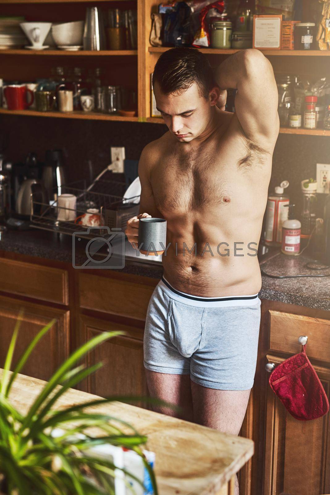 Royalty free image of Coffee is the perfect wake up call in the morning. a handsome young shirtless man drinking a cup of coffee in the kitchen at home. by YuriArcurs