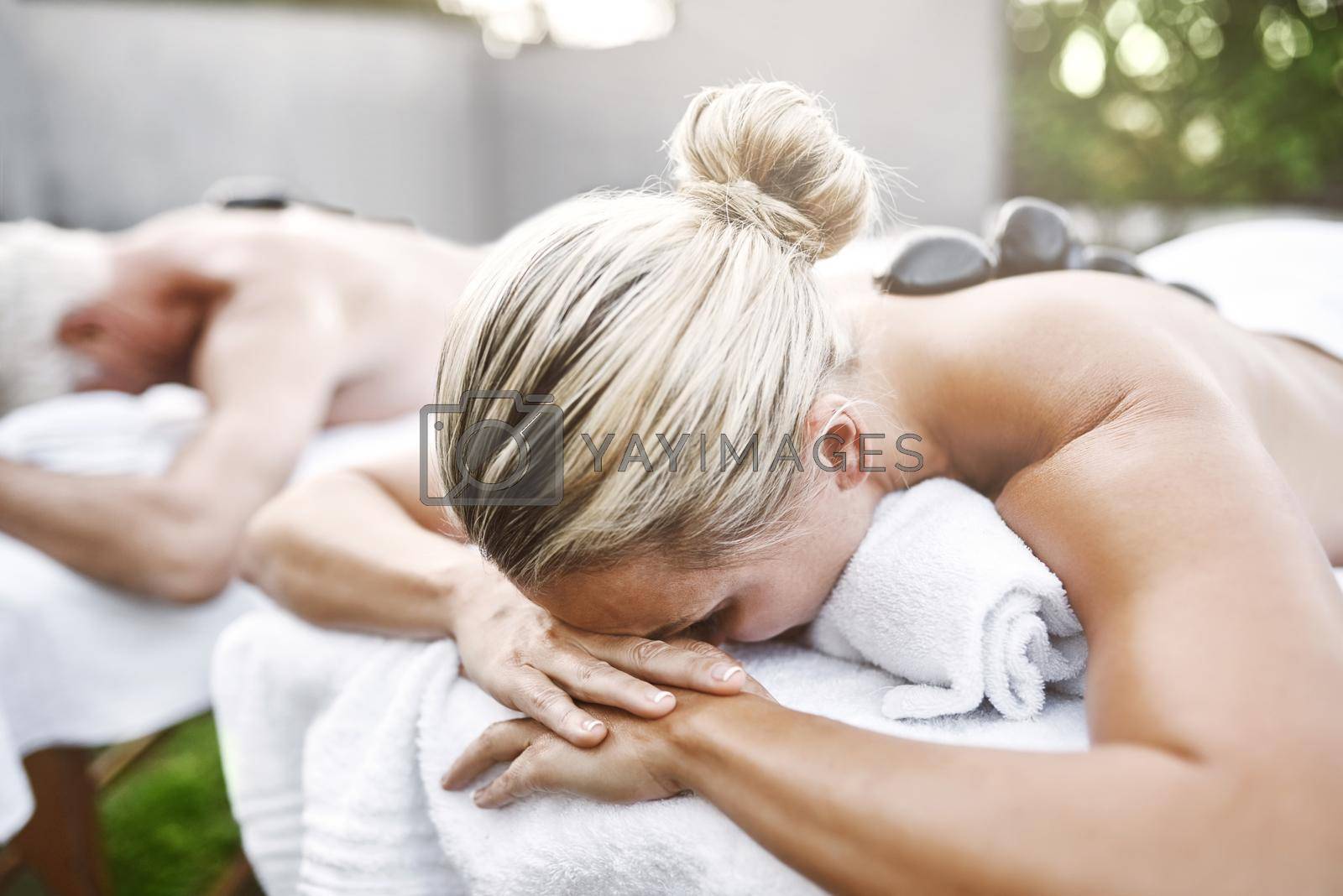 Royalty free image of Im not going anywhere right now. a carefree middle aged couple lying on massage beds while relaxing outside at a spa during the day. by YuriArcurs
